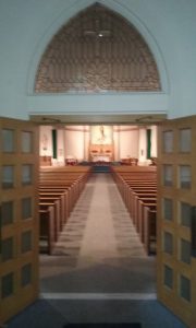 church doors open with pews and sanctuary