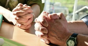 wife and husband with hands clasped at a table