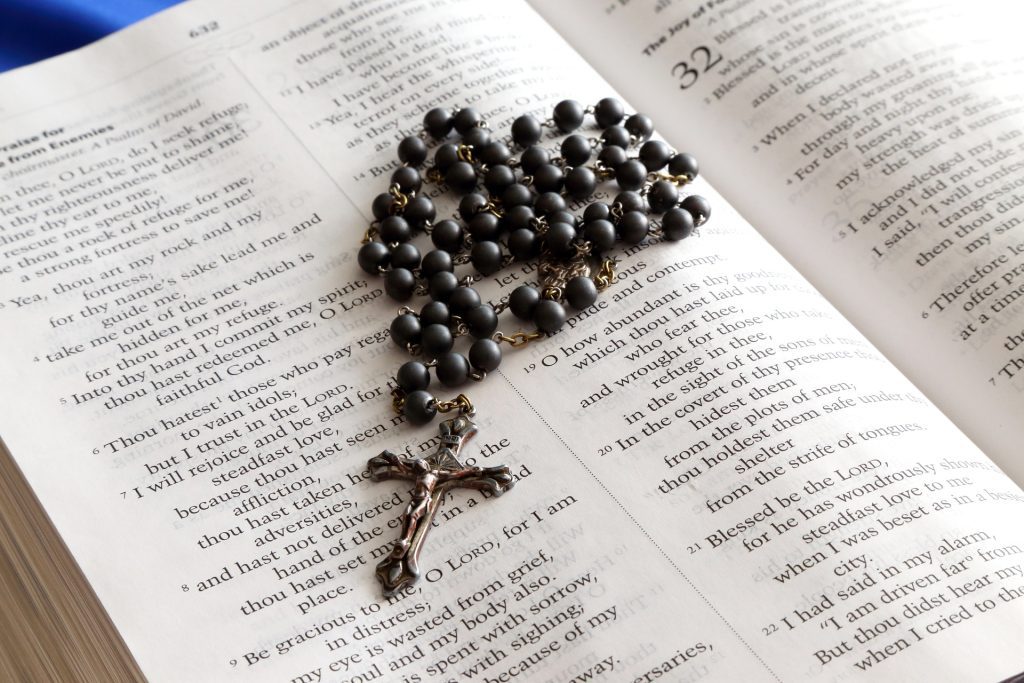 A bible is open with a rosary on top of the pages
