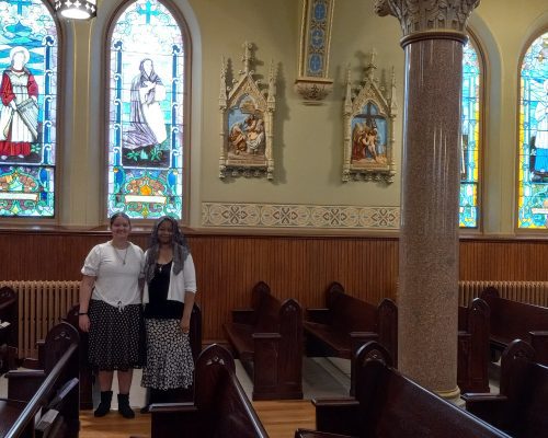 mother and daughter standing in front of stained glass windows