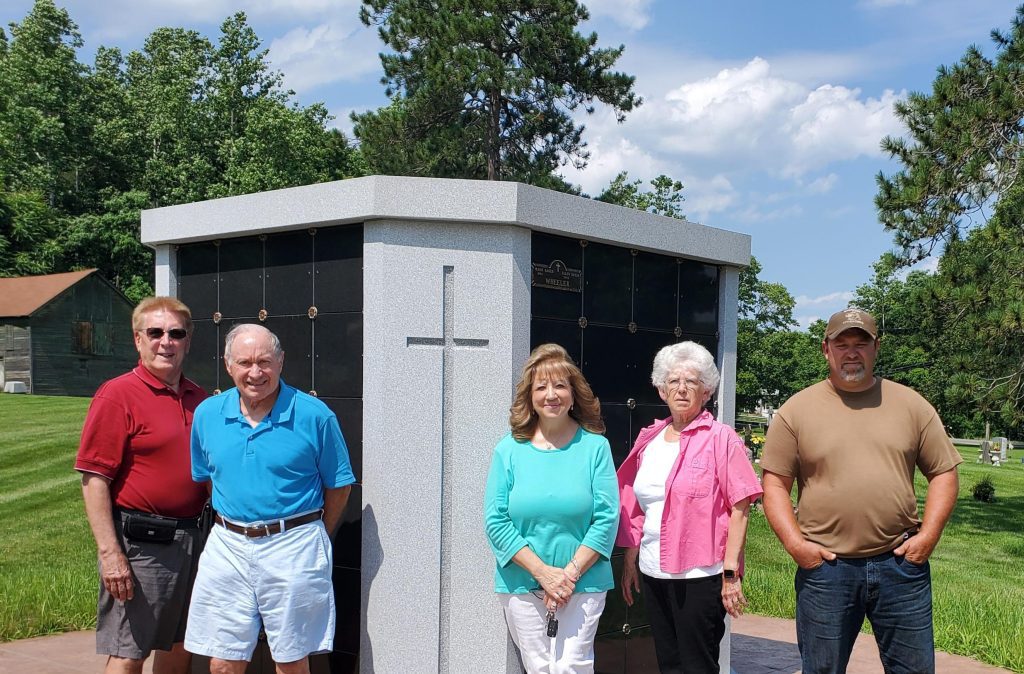 5 people stand in front of a columbarium at the cemetery