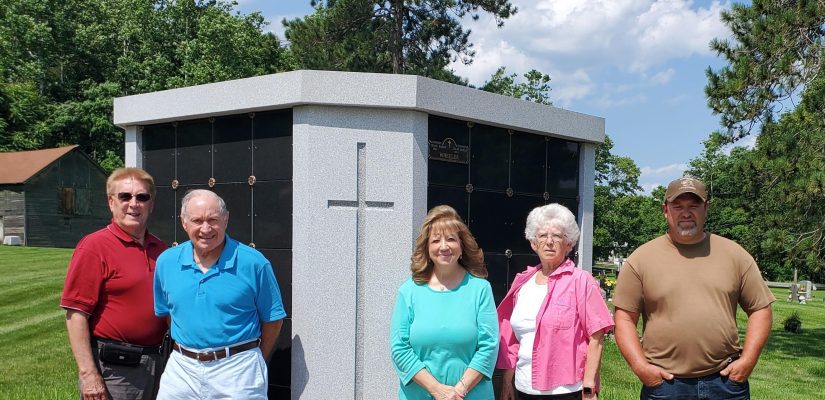 5 people stand in front of a columbarium at the cemetery