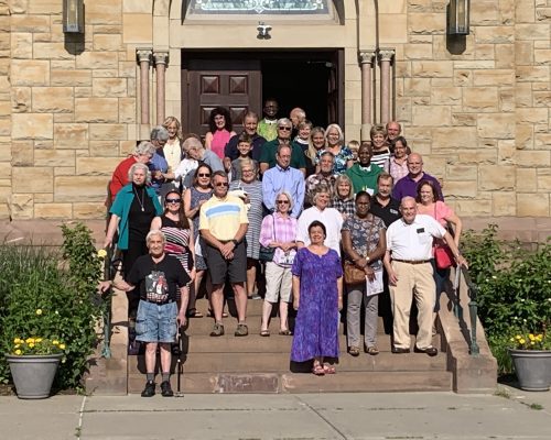 a group of people standing on steps outside Immaculate Conception Church