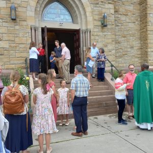people gather on steps after Mass talking with Priest