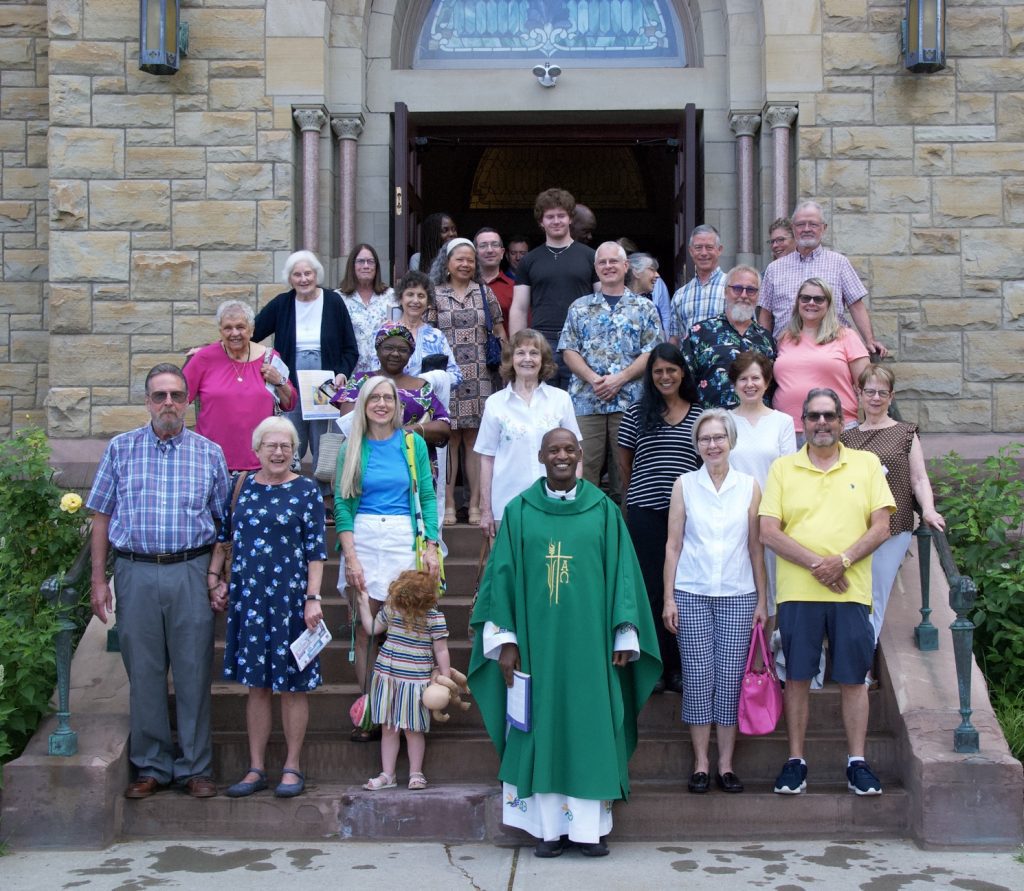 People gather on the steps of a church with the Priest.