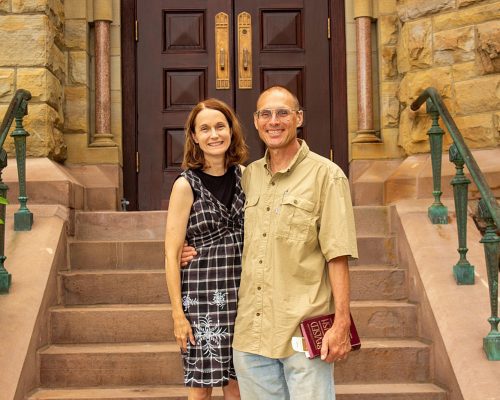 A couple stands at the bottom of the church steps