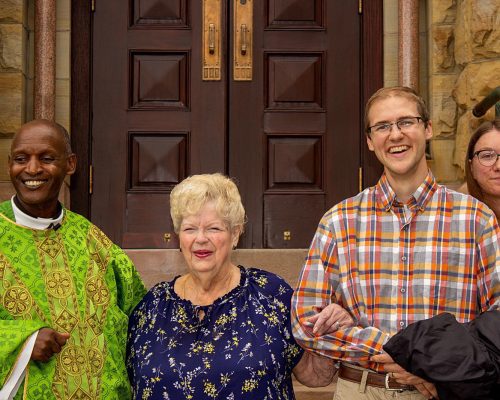 A Priest stands with a woman and a couple