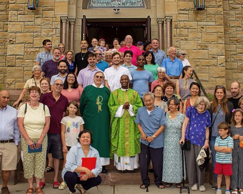 A group of people stand on the steps of the church.