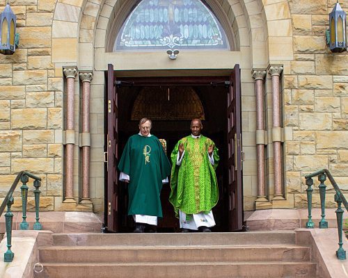 a priest and deacon walk out the church door