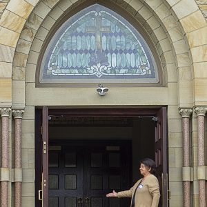 Woman greeter stands at the doorway of the church