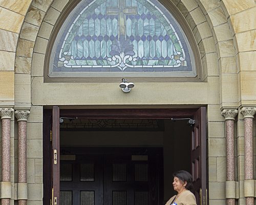 Woman greeter stands at the doorway of the church
