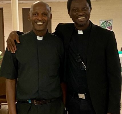 2 African men stand together with smiles