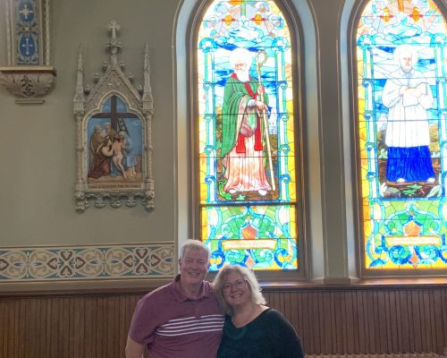 husband and wife stand in a church