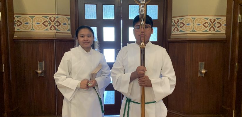 female and male teens robed in Altar Serving robes stand at back of the church