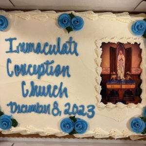 A cake displaying an image of the Blessed Mary Shrine with writing: Immaculate Conception Church December 8, 2023