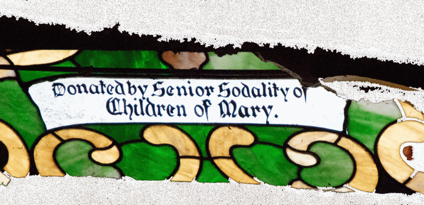 A portion of the stained glass window hidden behind the wall that reads "Donated by Senior Sodality of Children of Mary."