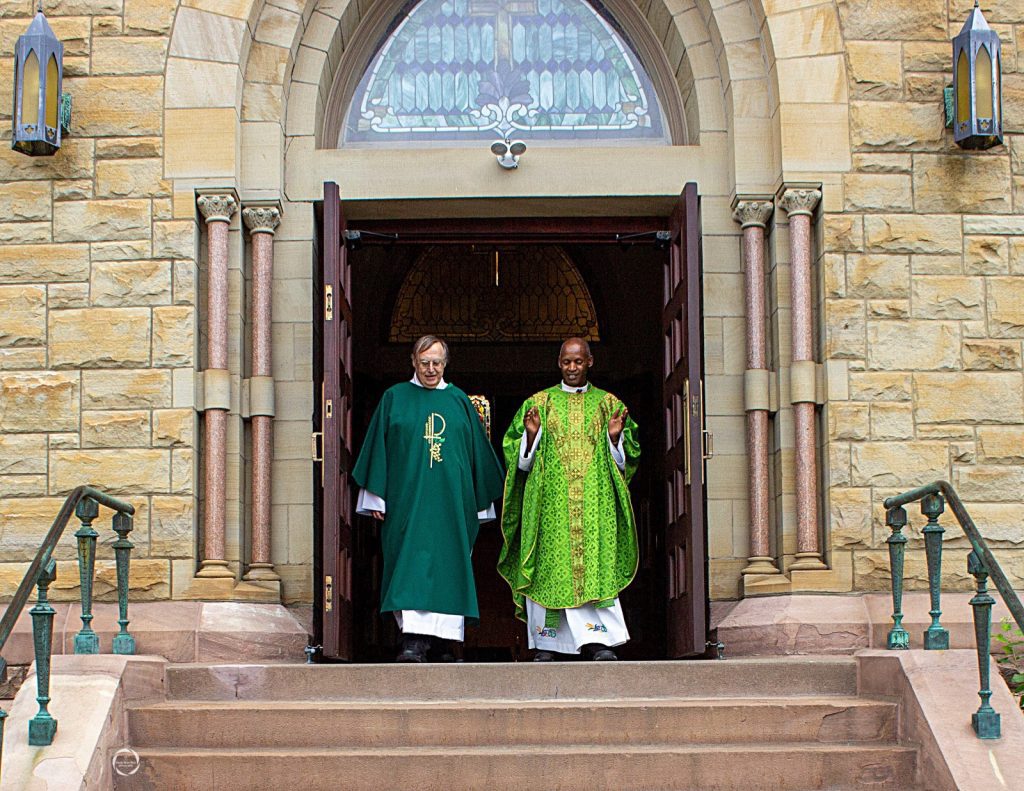 a priest and deacon walk out the church door