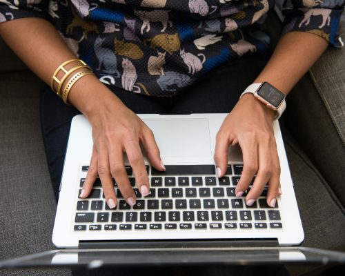 a woman's hands typing on keyboard